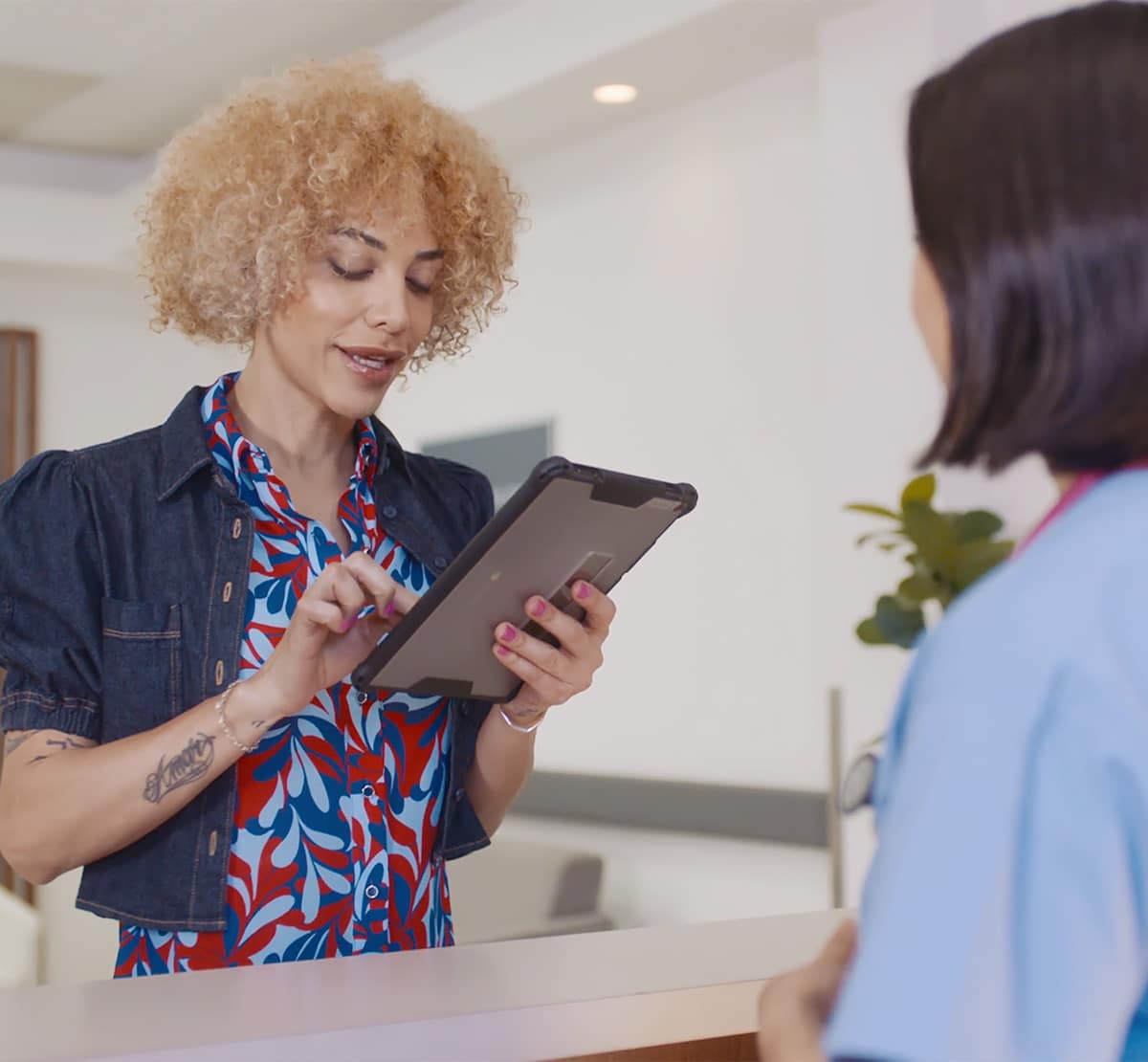 Woman holding a tablet with a office front desk staff