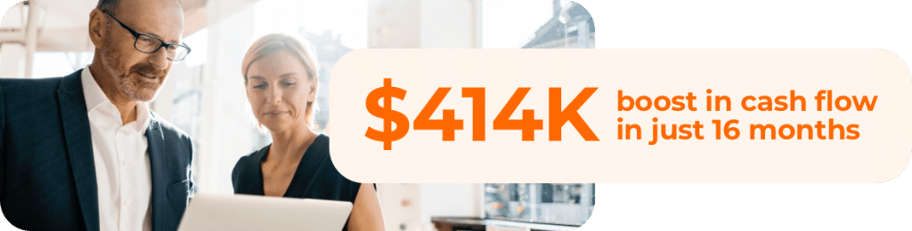 A businessman and business woman looking down at a laptop with the text: 4K boost in cash flow in just 16 months