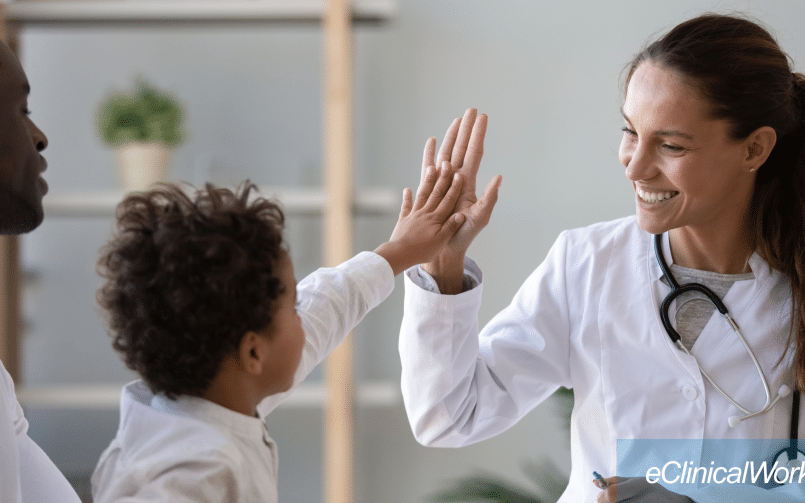 Provider high-fiving child patient in lap of parent with the eClinicalWorks logo in white in the lower right corner