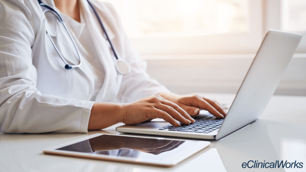 doctor sitting at laptop typing representing electronic health records (EHR)