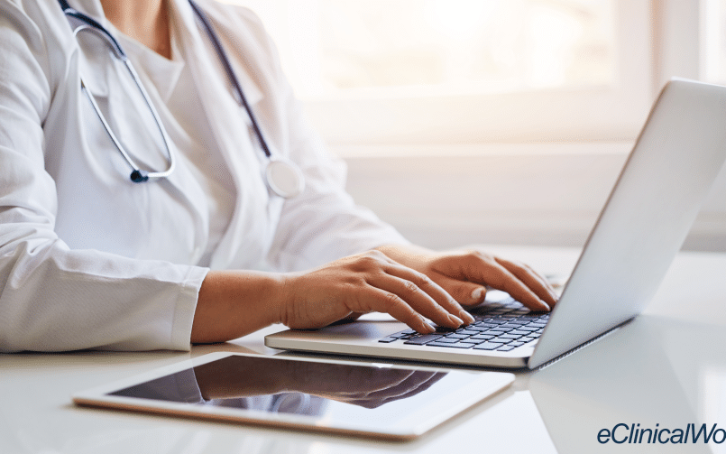 doctor sitting at laptop typing representing electronic health records (EHR)